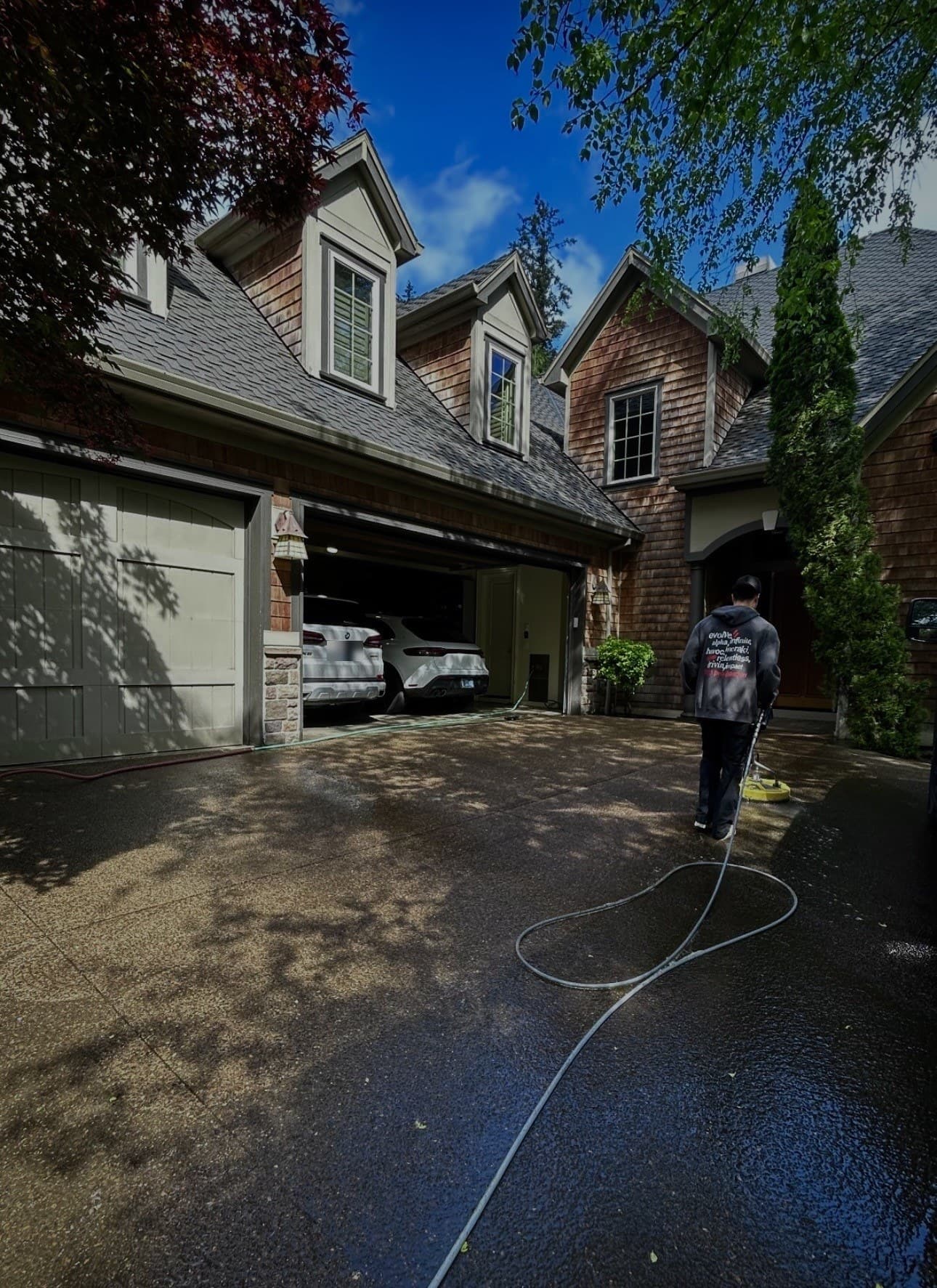 Clackamas Surface Co. technician pressure washing a driveway at an Oregon City home.